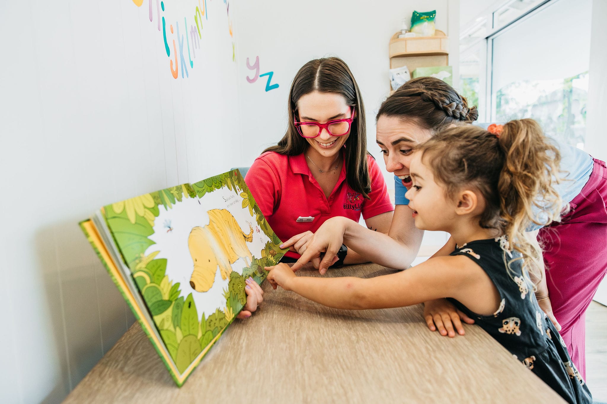 A child reading a picture book with speech pathologists