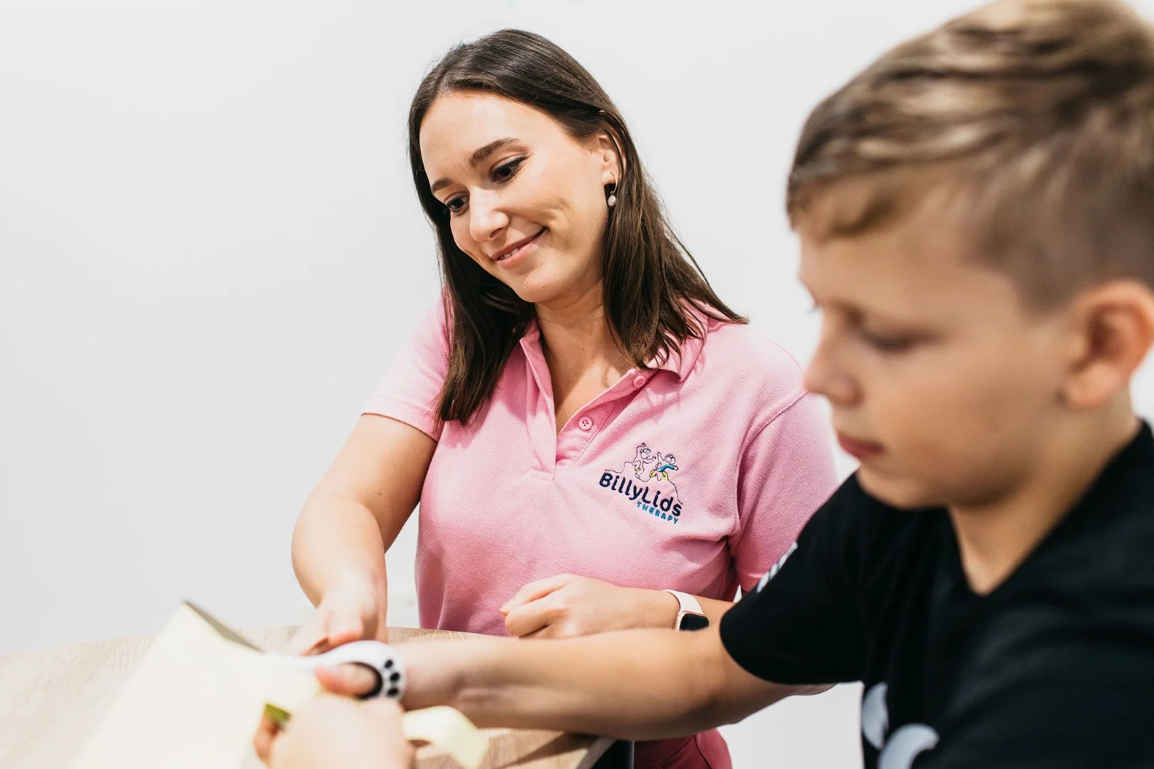 Woman showing a child how to use scissors in an occupational therapy session