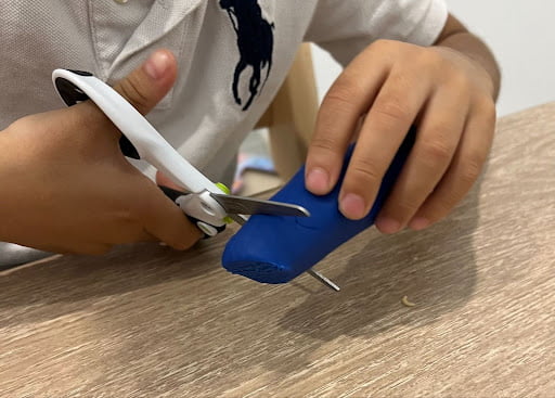 Child cutting playdough learning fine and gross motor skills