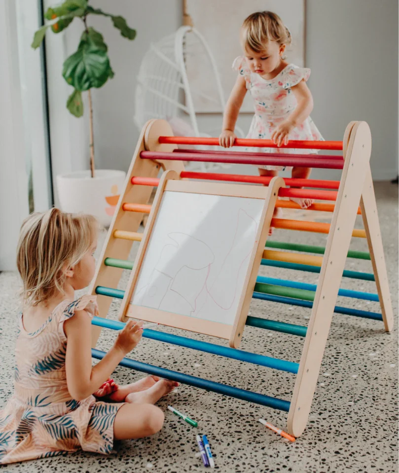 kids climbing on a pikler with whiteboard